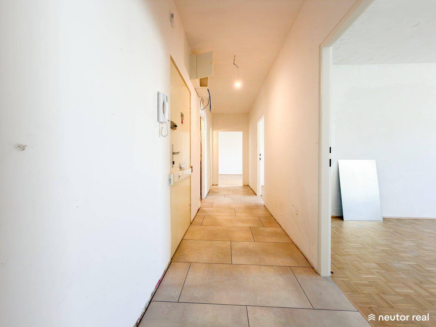 Langer Flur mit hellen Fliesen und Zugang zu verschiedenen Zimmern der Wohnung.