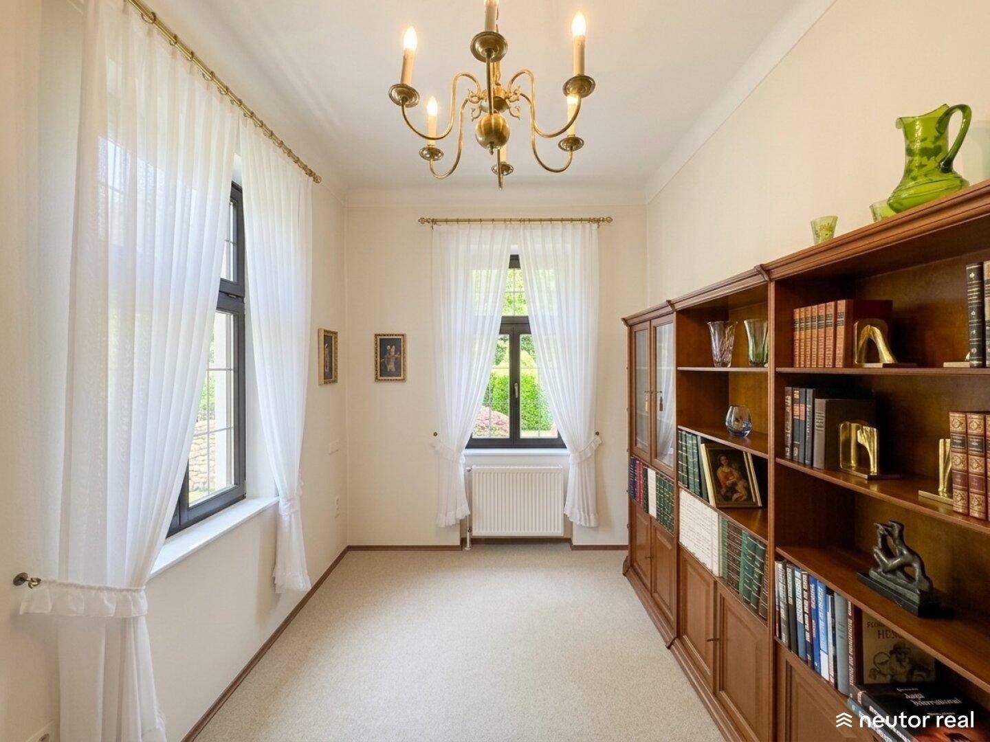 Ruhiges Arbeitszimmer mit großen Bücherregalen und klassischem Kronleuchter.