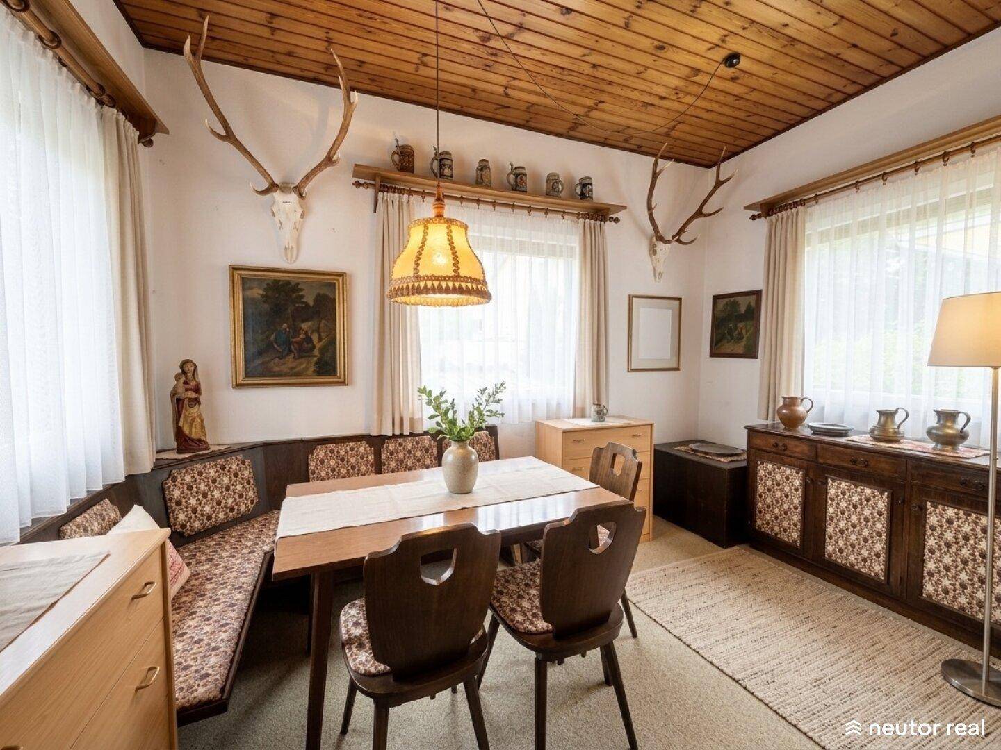 Gemütliches Esszimmer im alpinen Stil mit Holzdecke und Hirschgeweih-Dekoration.