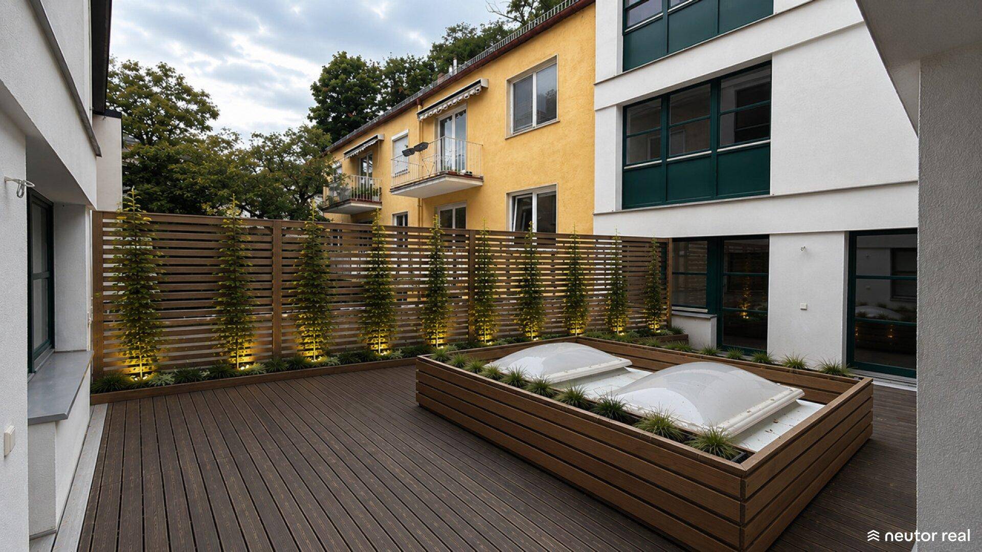 Attraktive Holzterrasse mit beleuchtetem Sichtschutz und Pflanzbeet für mehr Privatsphäre.