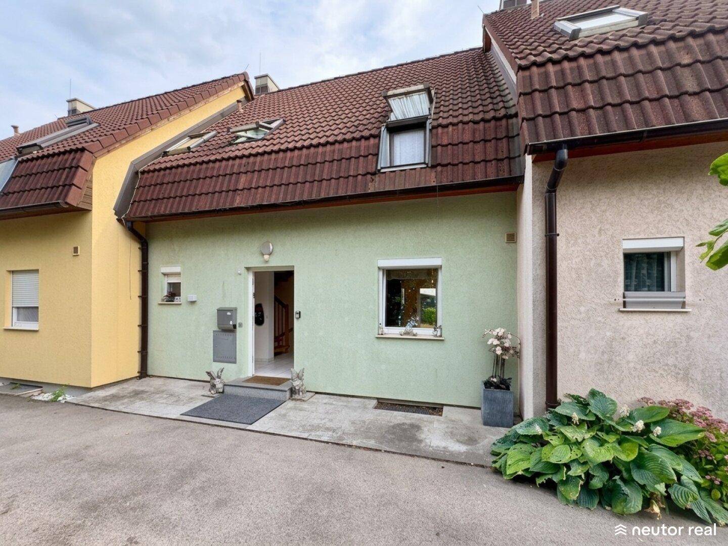 Eingangsbereich eines Reihenhauses mit gepflegter Fassade und kleinem Vorgarten.