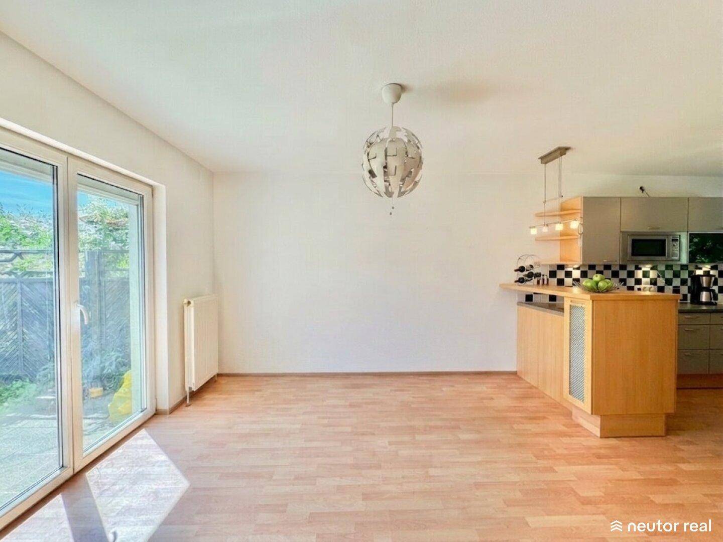 Offener Wohn- und Essbereich mit Laminatboden und direktem Zugang zum Garten.