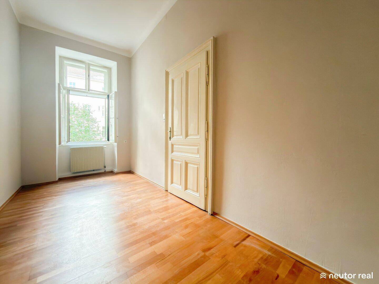 Leerer Raum mit Parkettboden, einer Tür und einem Fenster, bereit zur individuellen Gestaltung.