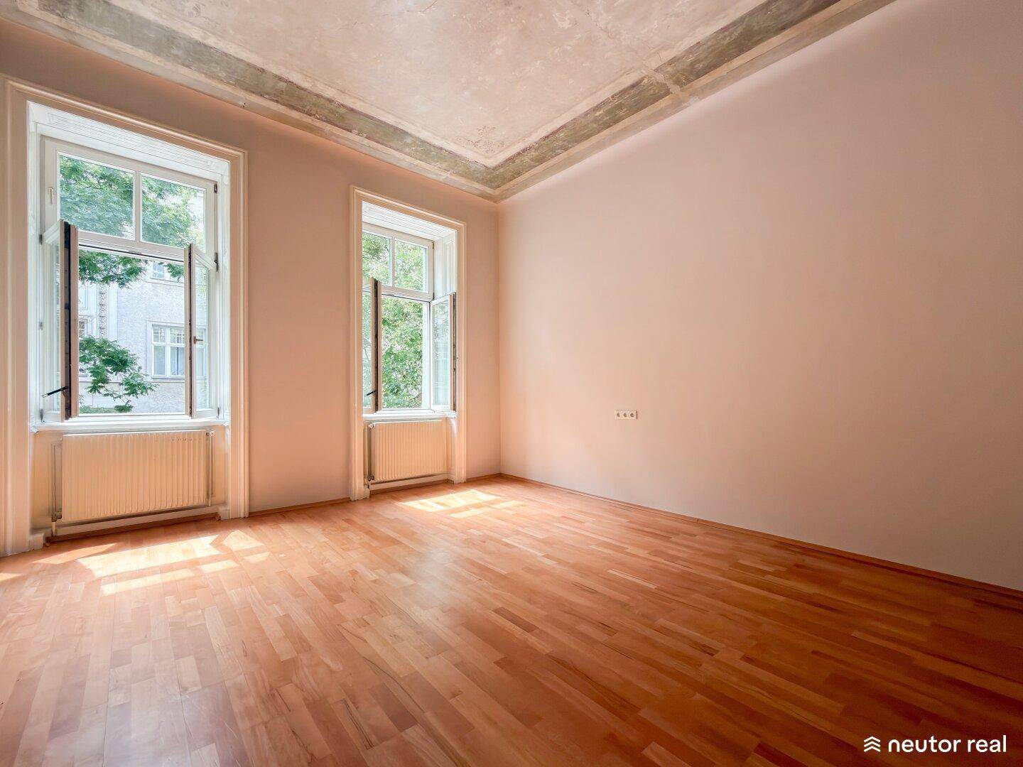 Lichtdurchfluteter leerer Raum mit Parkettboden und hohen Fenstern, ideal für individuelle Gestaltung.