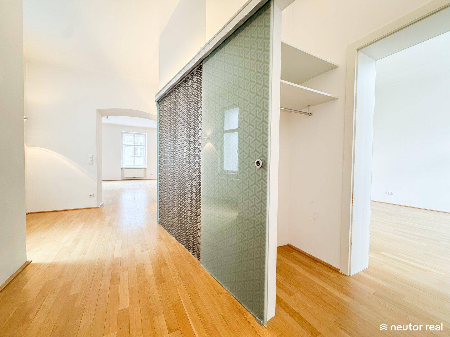 Geräumiger Flur mit Holzboden und einer eleganten Schiebetür, die einen Einbauschrank verbirgt.