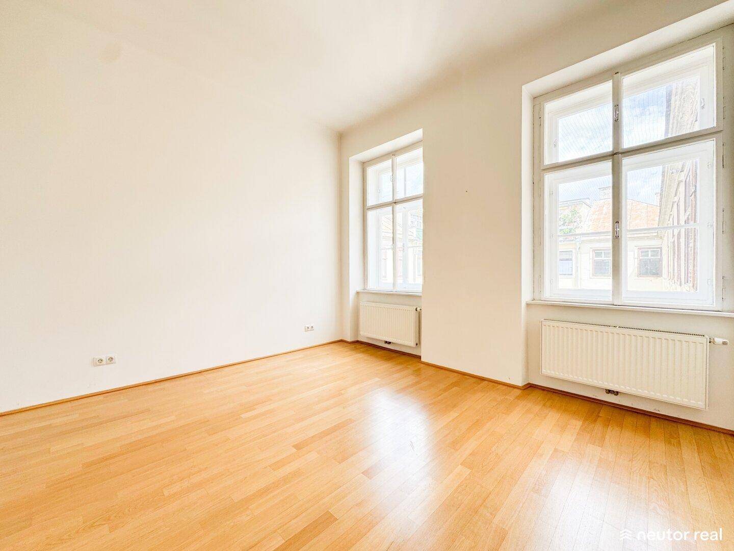 Geräumiges Schlafzimmer mit Holzboden, hohen Fenstern und viel natürlichem Licht.