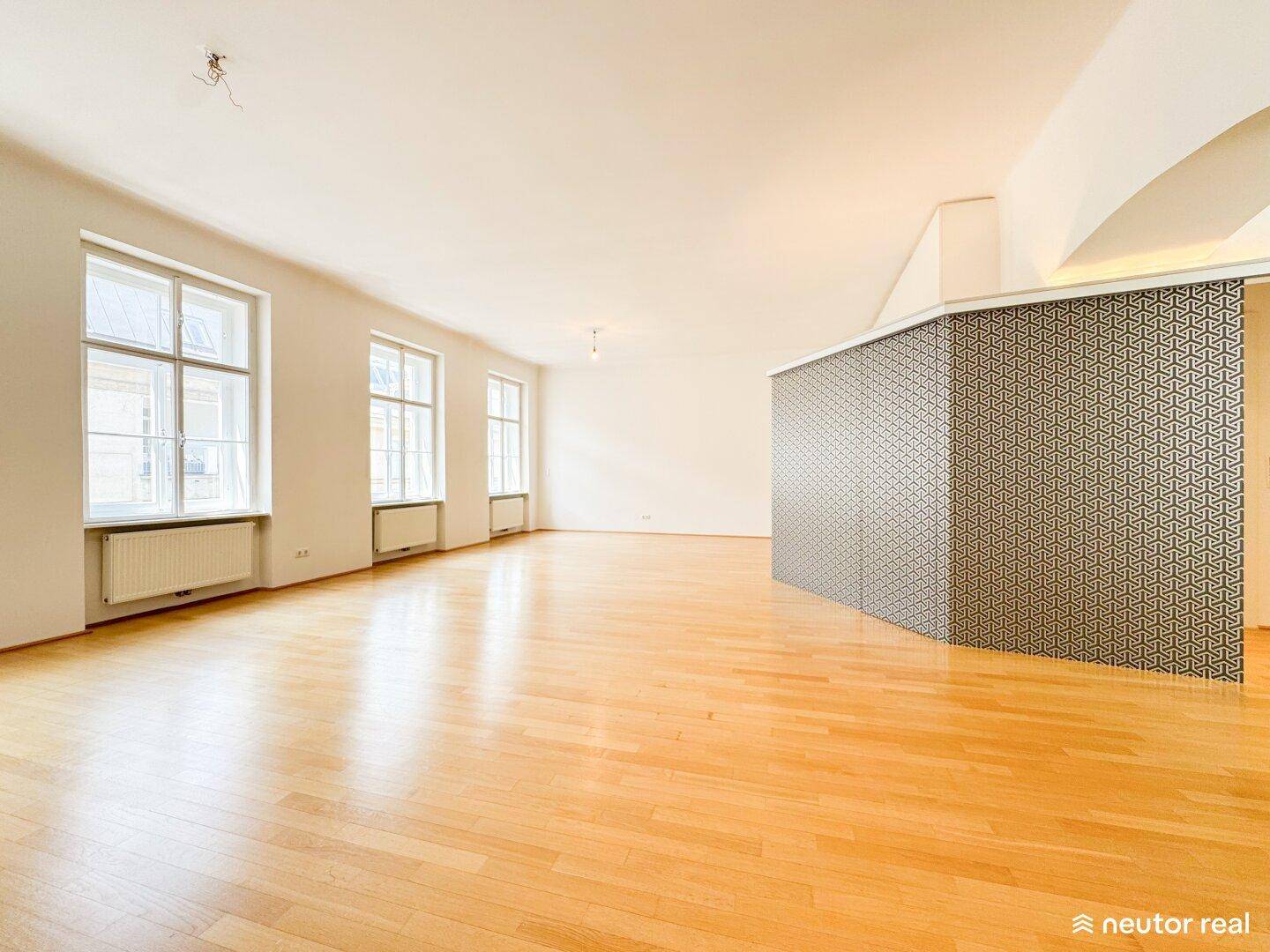 Heller, geräumiger Wohnbereich mit Holzboden und dekorativer Wandverkleidung, bereit zur Einrichtung.