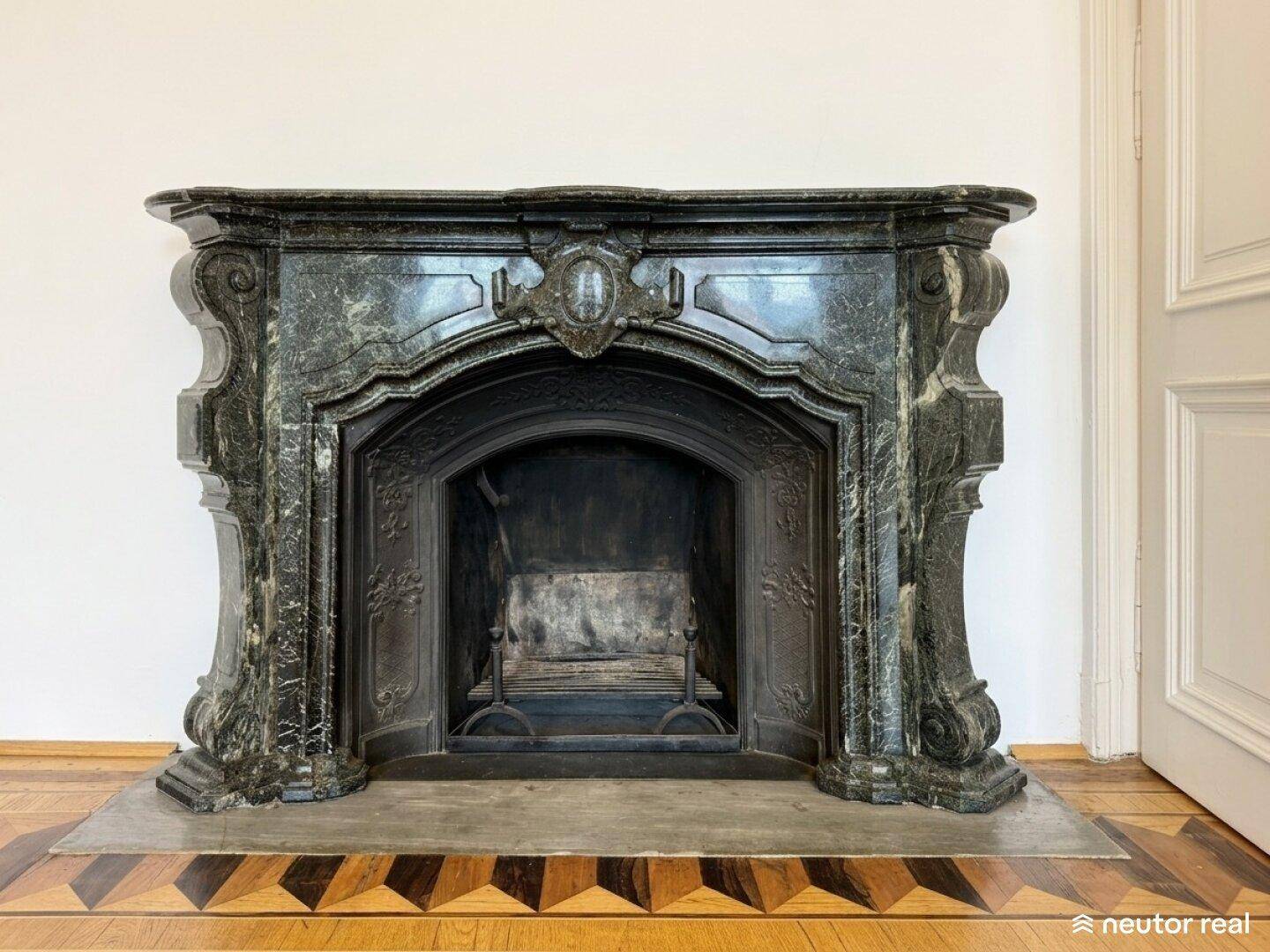 Detailaufnahme eines opulenten Kamins aus dunklem Marmor mit kunstvollen Verzierungen.