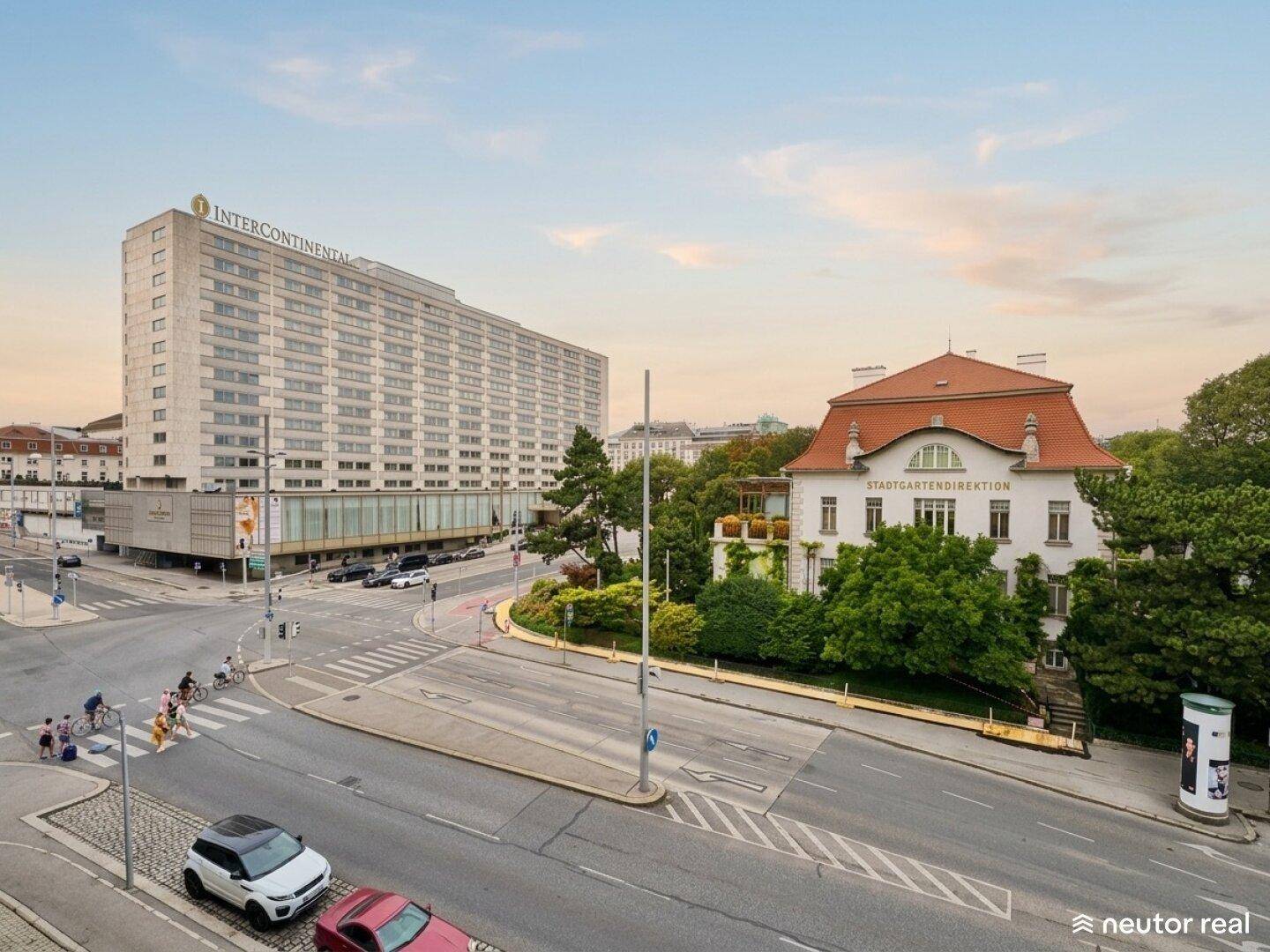 Luftaufnahme einer Stadtkreuzung mit modernen und historischen Gebäuden sowie viel Grün.