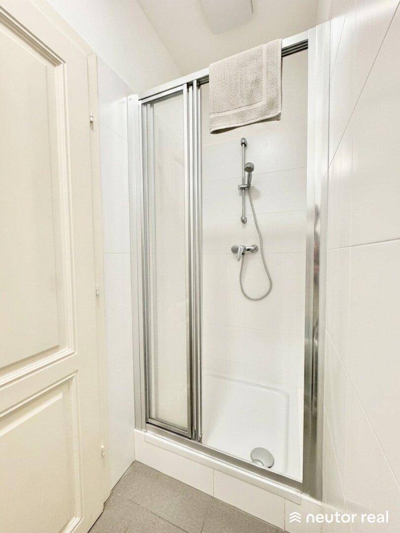 Modernes Badezimmer mit weiß gefliester Duschkabine und Handtuchhalter.