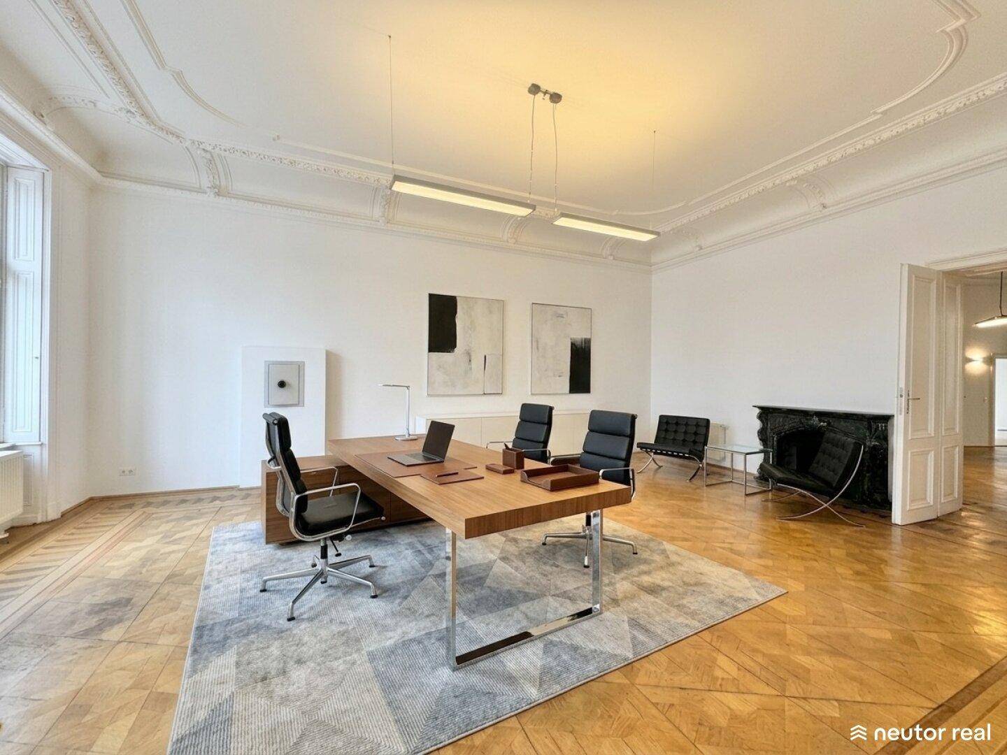 Geräumiges Büro mit klassischem Parkettboden, Stuckdecke und einem modernen Schreibtischbereich.