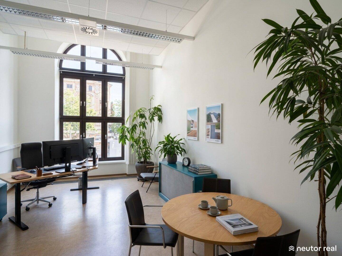 Helles Büro mit hohen Decken, Rundbogenfenstern und einem kleinen Besprechungsbereich.