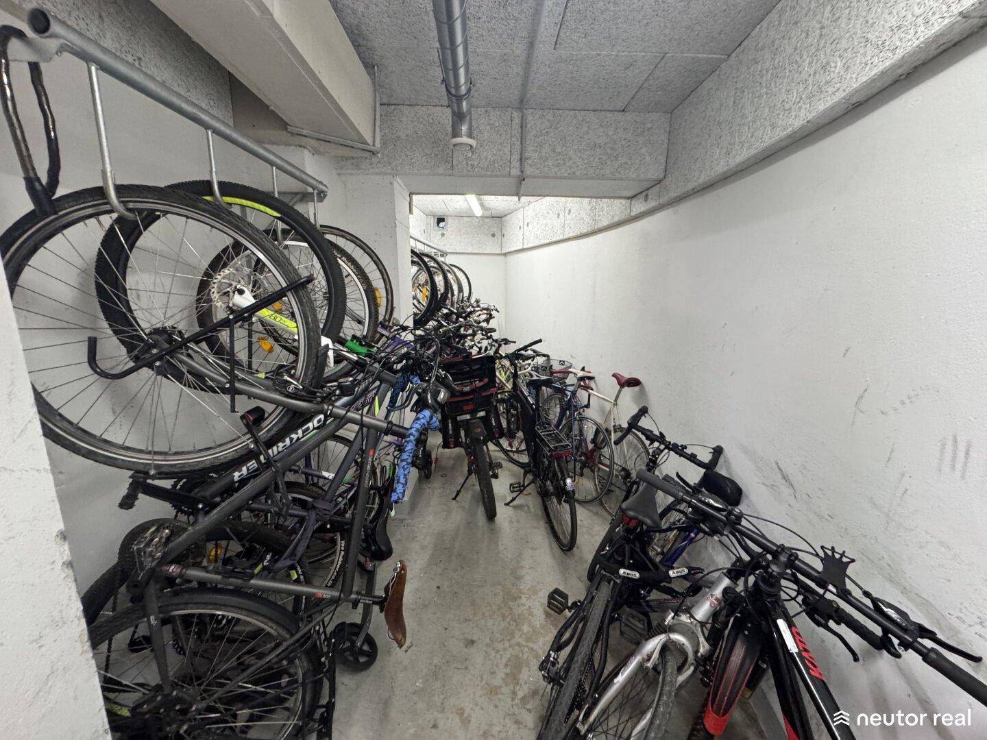 Gemeinschaftlicher Fahrradraum im Untergeschoss mit vielen abgestellten Fahrrädern und Aufhängesystemen.