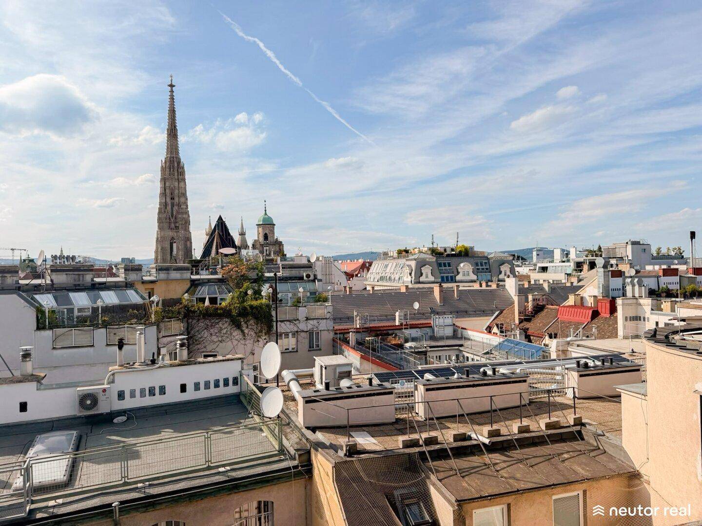Panoramablick über die Dächer der Stadt mit historischem Kirchturm unter blauem Himmel.