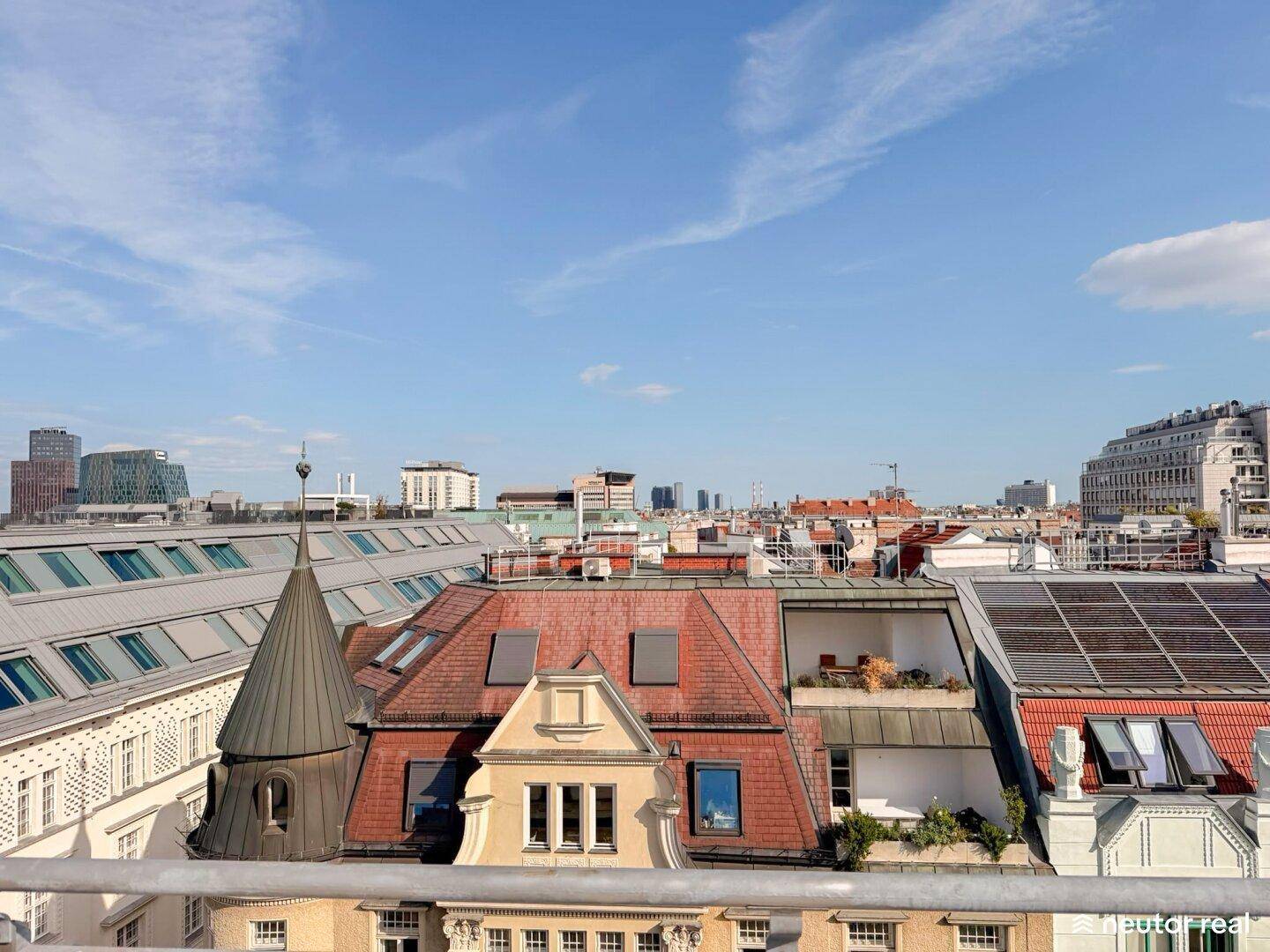 Weitläufiger Blick über die vielfältige Dachlandschaft der Stadt mit modernen und historischen Gebäuden.