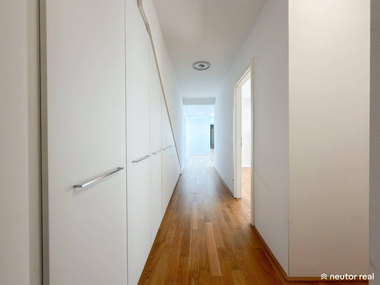 Heller Flur mit Holzboden und praktischen Einbauschränken entlang der Wand für zusätzlichen Stauraum.