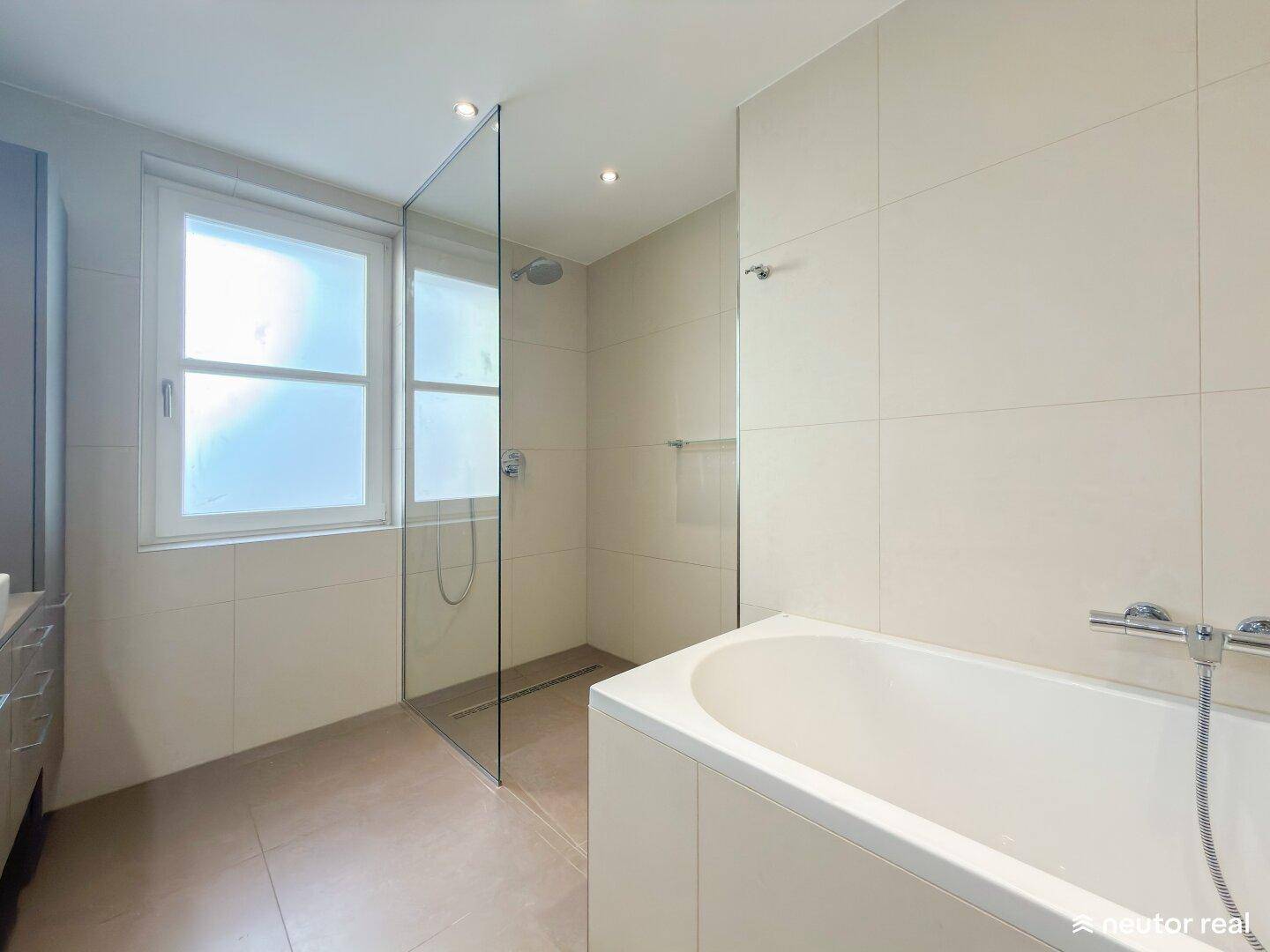 Modernes Badezimmer mit begehbarer Dusche, Badewanne und Fenster für natürliches Tageslicht.