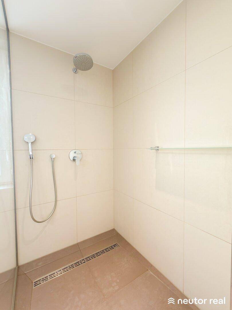Großzügige, begehbare Dusche mit Regenduschkopf und modernen Fliesen im Badezimmer.