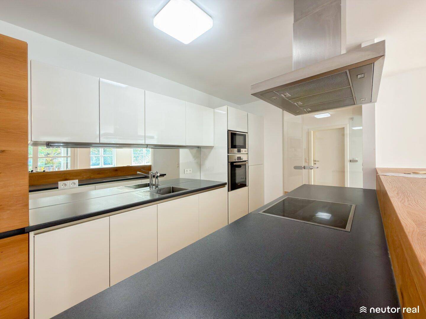 Stilvolle Küche mit Induktionskochfeld, Dunstabzugshaube und integrierten Backofen in modernem Design.