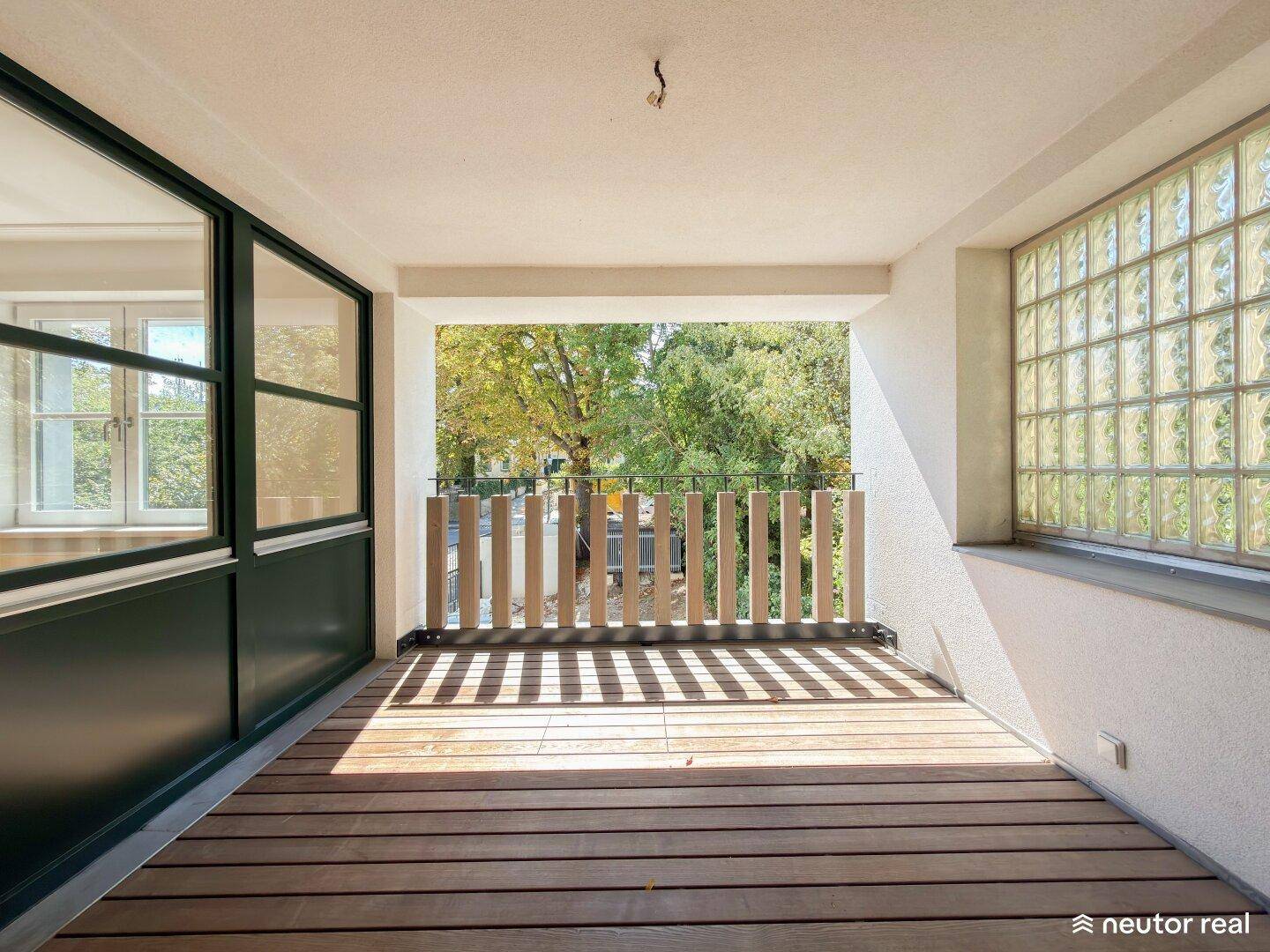 Überdachte Loggia mit Holzdeck und Blick ins Grüne, ideal für entspannte Stunden im Freien.