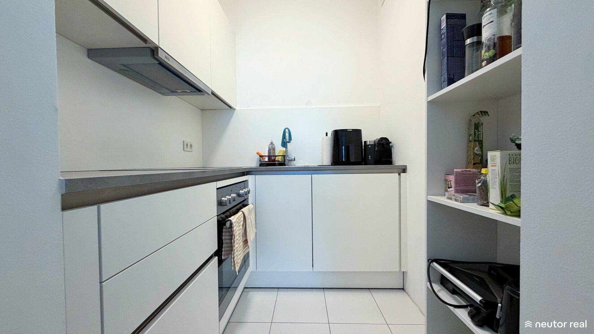 Funktionale Küche mit weißen Schränken, integriertem Backofen und Dunstabzugshaube.