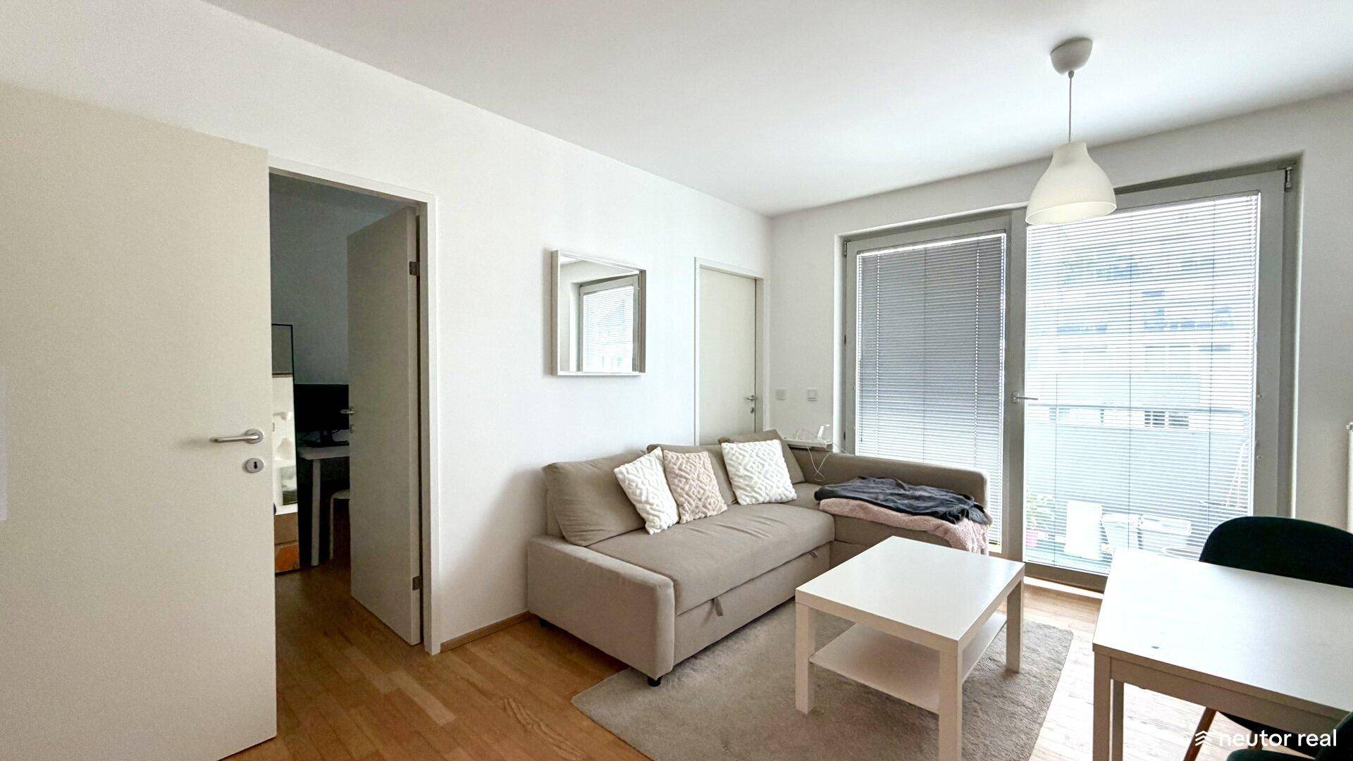 Gemütlicher Wohn-Essbereich mit Sofa, Esstisch und Zugang zu einem Balkon oder einer Terrasse.