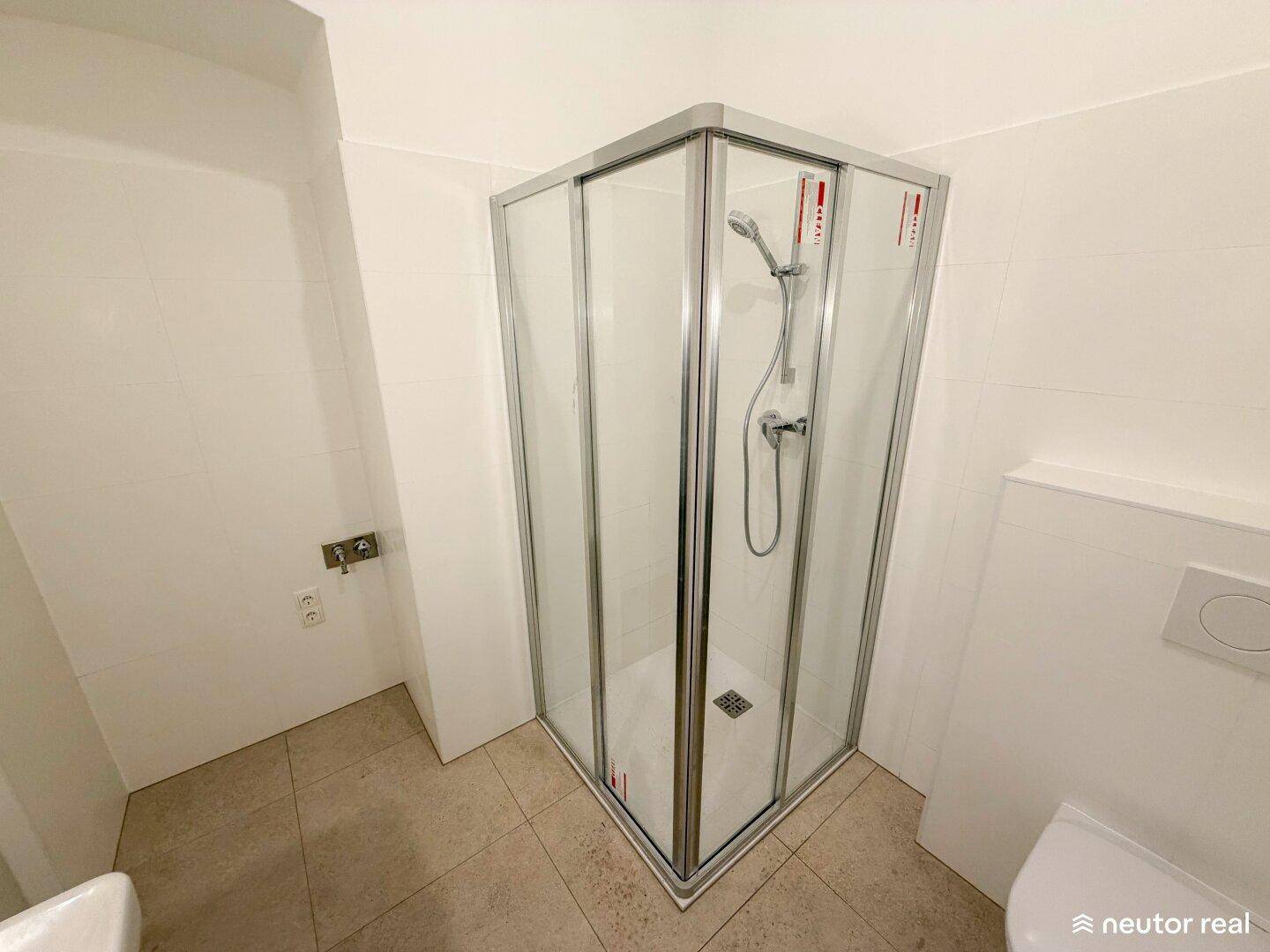 Modernes Badezimmer mit Eckduschkabine und weißen Fliesen, funktional und sauber.