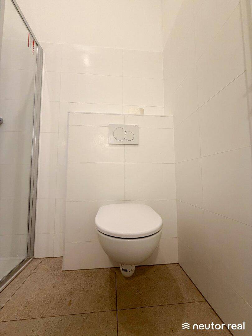 Wandhängendes WC in einem hell gefliesten Badezimmer, modern und platzsparend.
