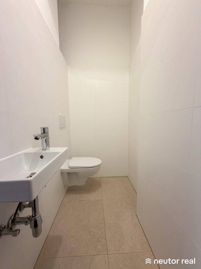 Kleines Gäste-WC mit wandhängendem WC und Handwaschbecken, komplett gefliest.
