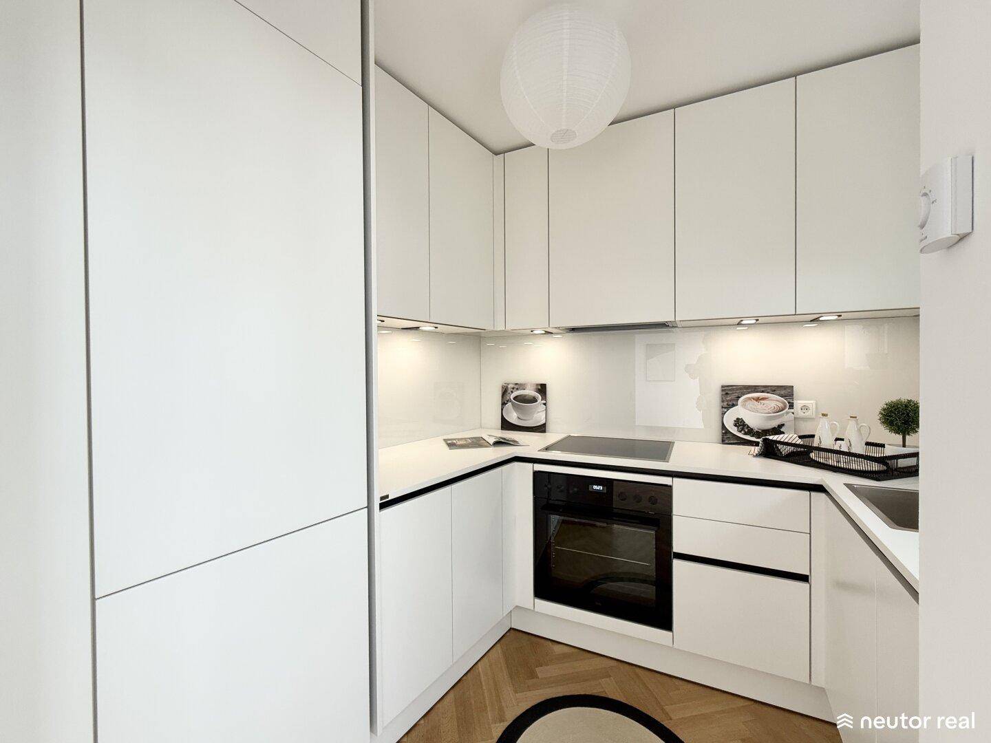 Moderne weiße Küche mit Hochglanzfronten, integrierten Geräten und hellem Ambiente.