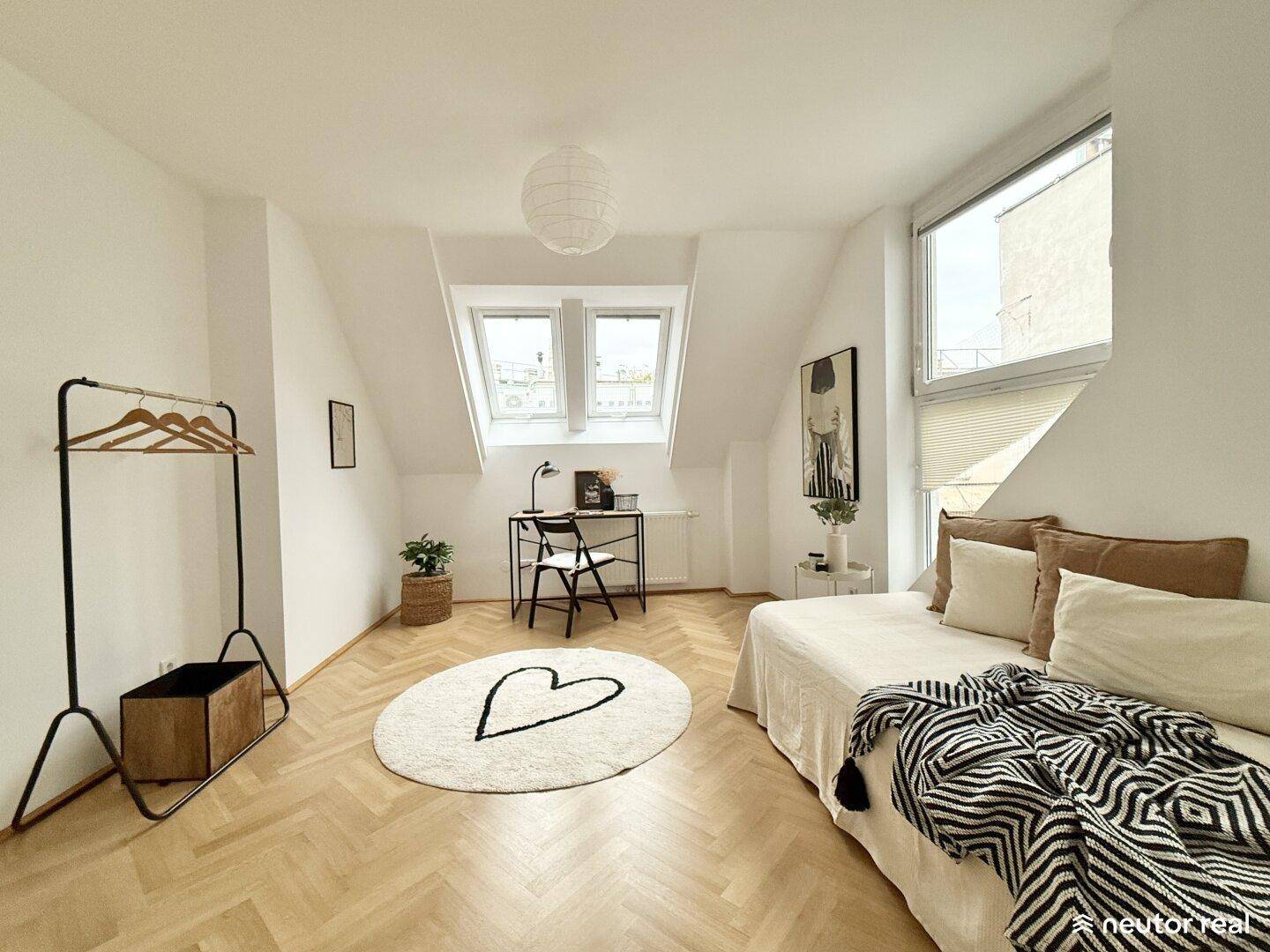 Helles Schlafzimmer im Dachgeschoss mit Schreibtisch, Dachfenstern und Fischgrätparkett.