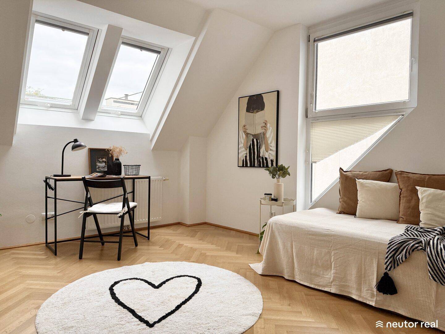 Helles Schlafzimmer im Dachgeschoss mit Schreibtisch, Dachfenstern und Fischgrätparkett.