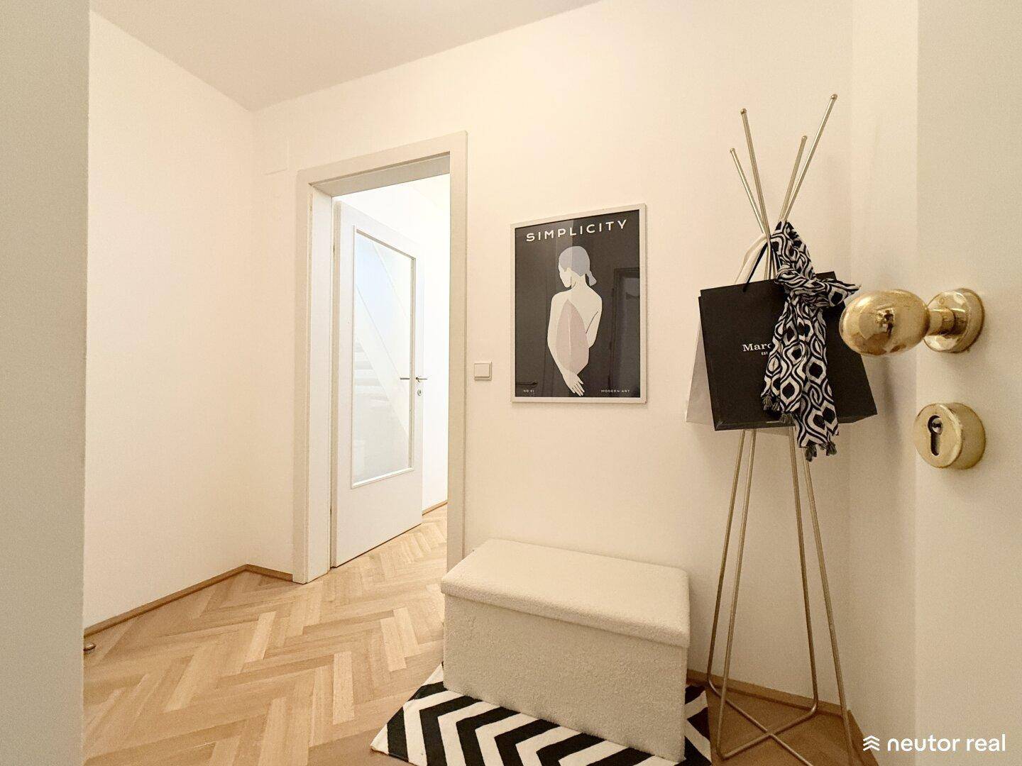 Heller Eingangsbereich mit Fischgrätparkett, moderner Garderobe und weißer Zimmertür.