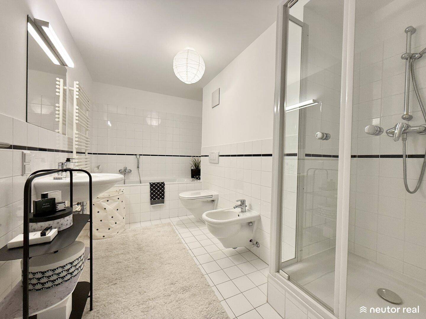 Modernes Badezimmer mit Badewanne, Dusche, Bidet, Einzelwaschbecken und weißen Fliesen.