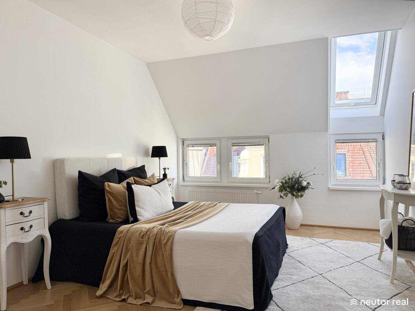 Gemütliches Schlafzimmer mit Dachfenstern, Fischgrätparkett und moderner Einrichtung im Dachgeschoss.