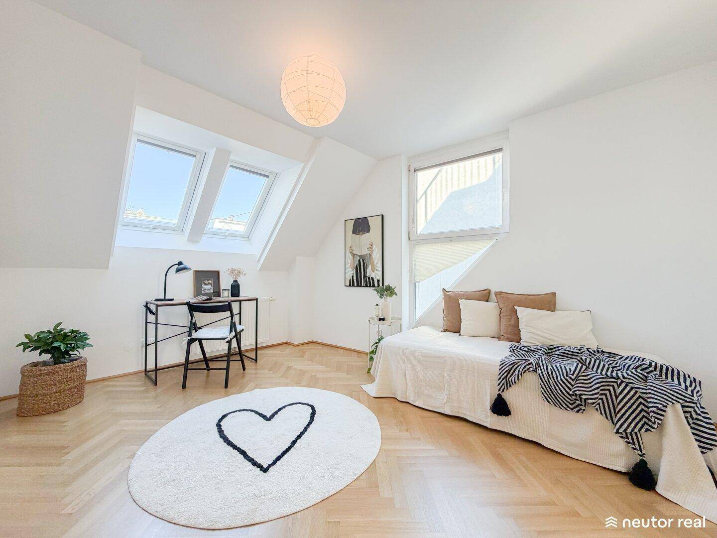 Lichtdurchflutetes Zimmer mit Schreibtisch, Tagesbett und mehreren Dachfenstern, perfekt zum Arbeiten und Schlafen.