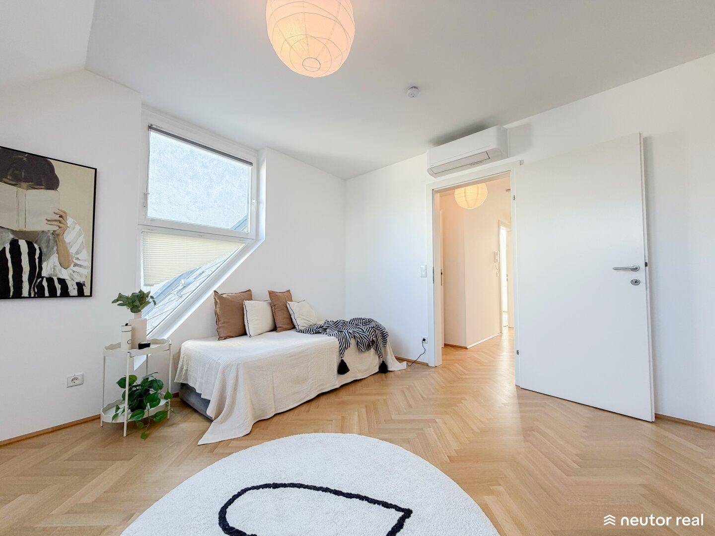 Helles Schlafzimmer mit Dachschrägenfenstern, Parkettboden und Klimaanlage für angenehmes Raumklima.