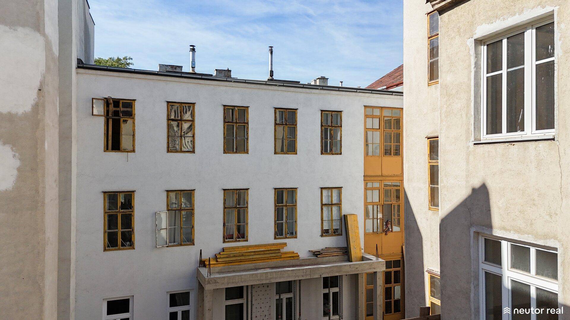 Blick auf die Rückseite eines Altbaus mit vielen Fenstern und einem Innenhofbereich.