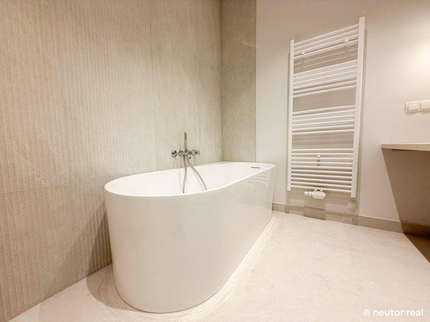 Modernes Badezimmer mit einer eleganten freistehenden Badewanne und beheiztem Handtuchhalter.