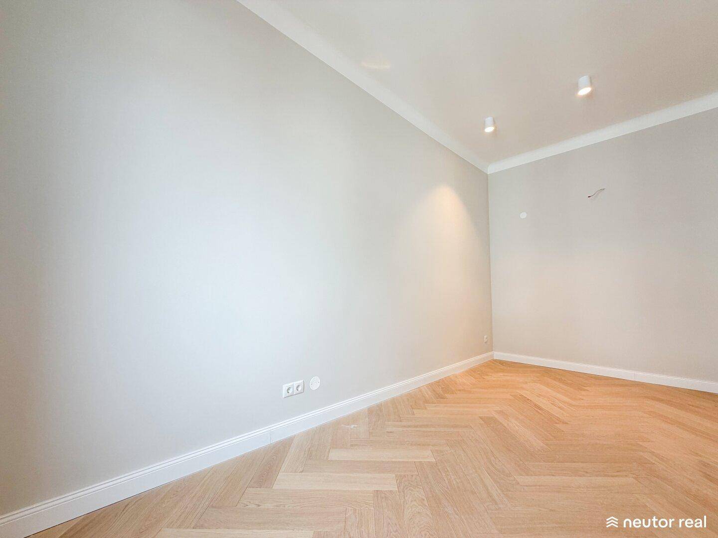 Geräumiges Zimmer mit hellem Fischgrätparkett und modernen Deckenspots, bereit zur Einrichtung.