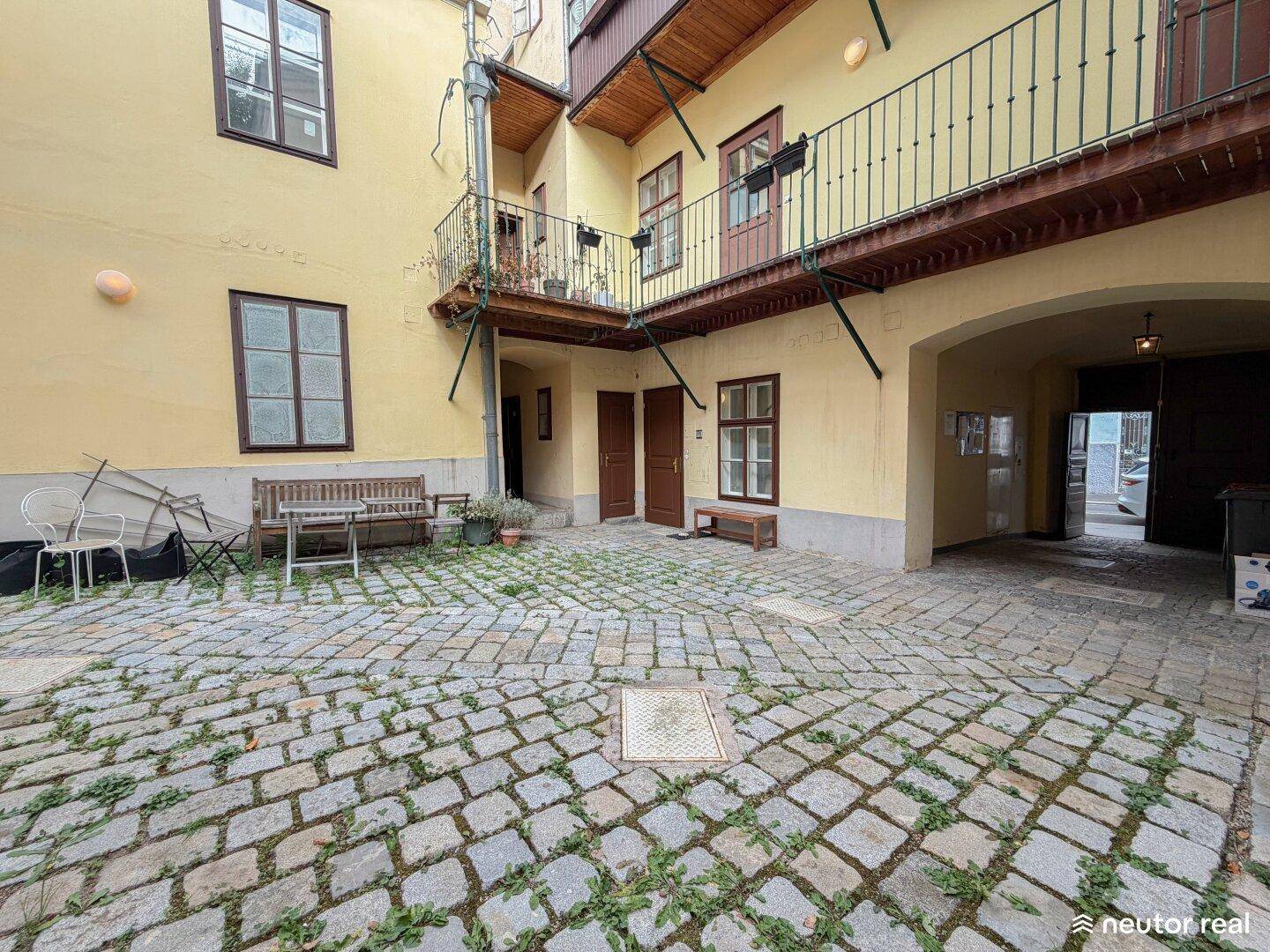 Geräumiger Innenhof mit Kopfsteinpflaster, Sitzgelegenheiten und Balkonen an den umliegenden Gebäuden.