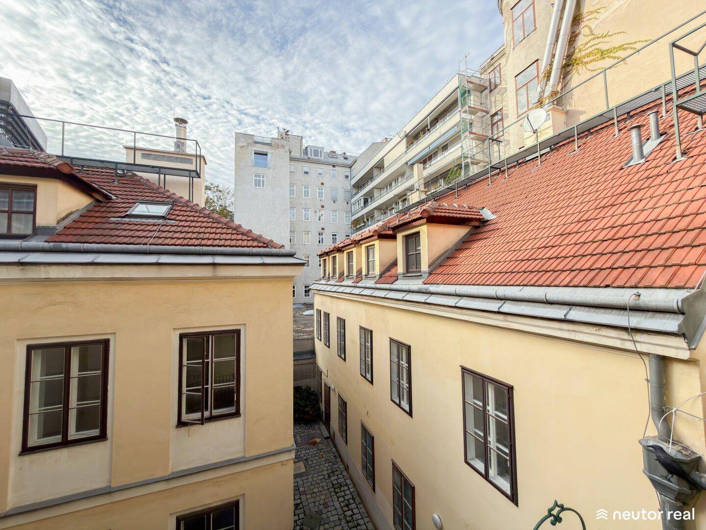 Blick auf die Dächer und Innenhöfe der umliegenden Gebäude unter einem bewölkten Himmel.