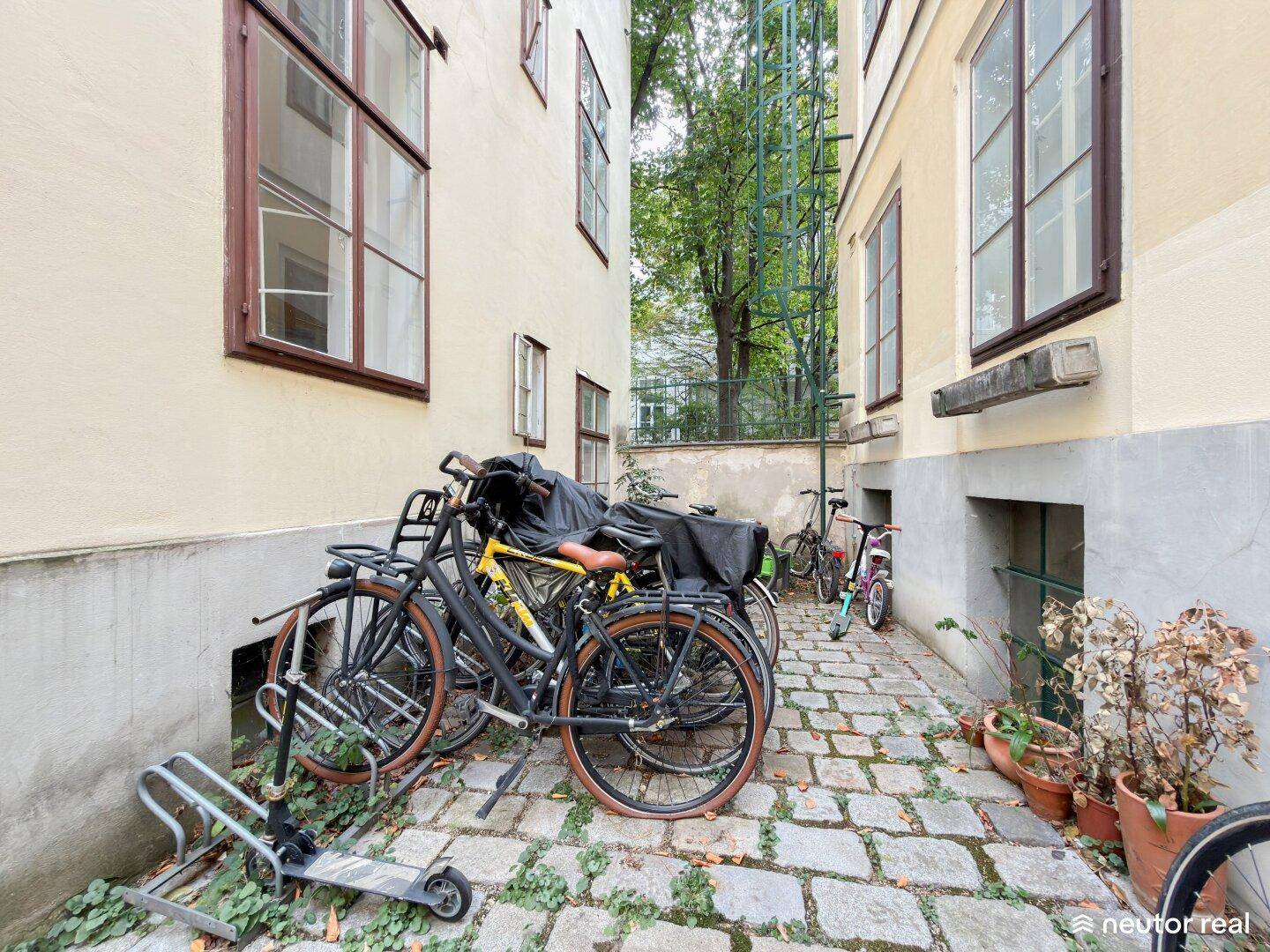 Kleiner Innenhof mit Kopfsteinpflaster, Fahrrädern und Topfpflanzen zwischen den Gebäuden.