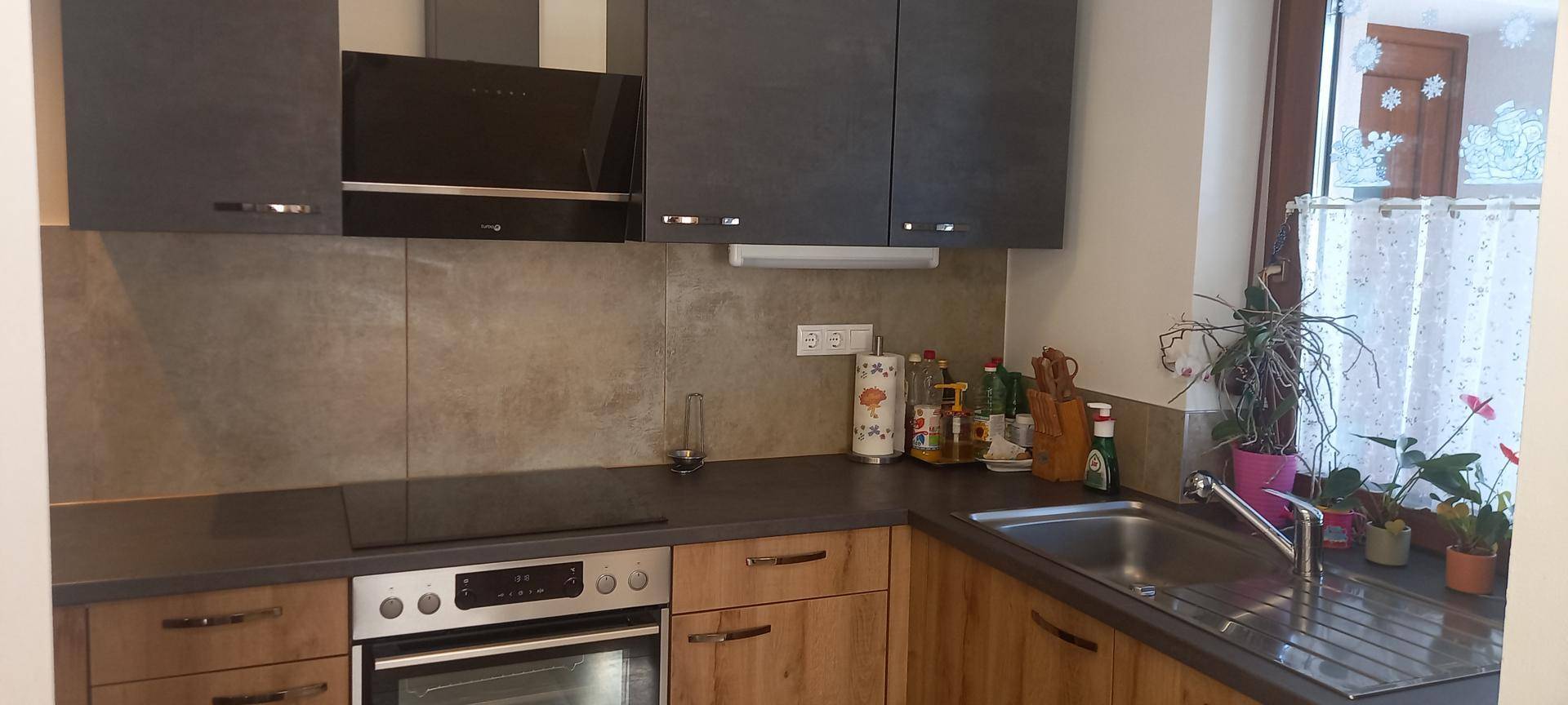 Moderne Küche mit dunklen Oberschränken, Holzelementen und integrierten Geräten.