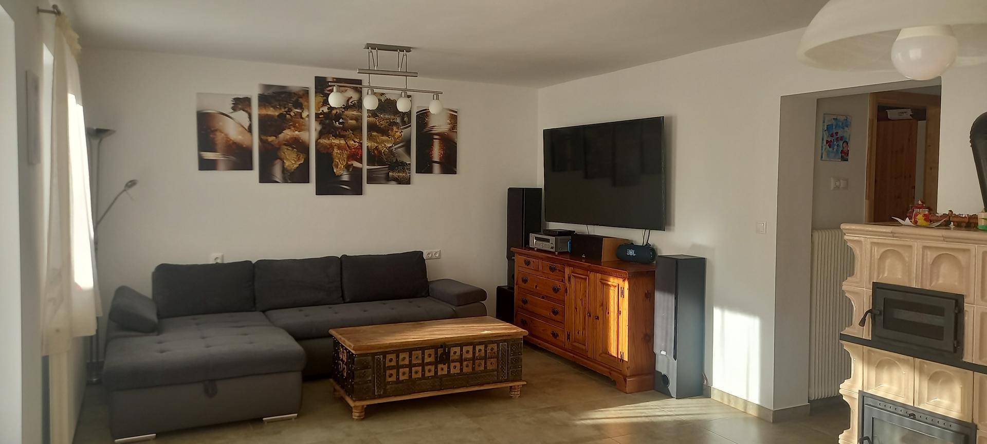 Gemütliches Wohnzimmer mit großem Ecksofa, Holztisch und Kachelofen im traditionellen Stil.