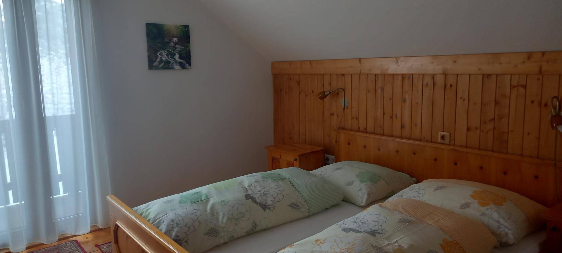 Gemütliches Schlafzimmer mit Holzvertäfelung, Doppelbett und Zugang zu einem Balkon.