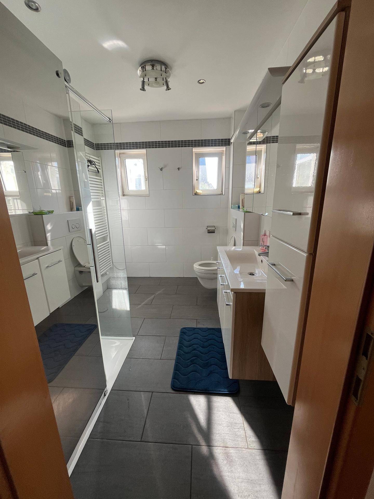 Modernes Badezimmer mit ebenerdiger Dusche, Einzelwaschbecken und Fenster.