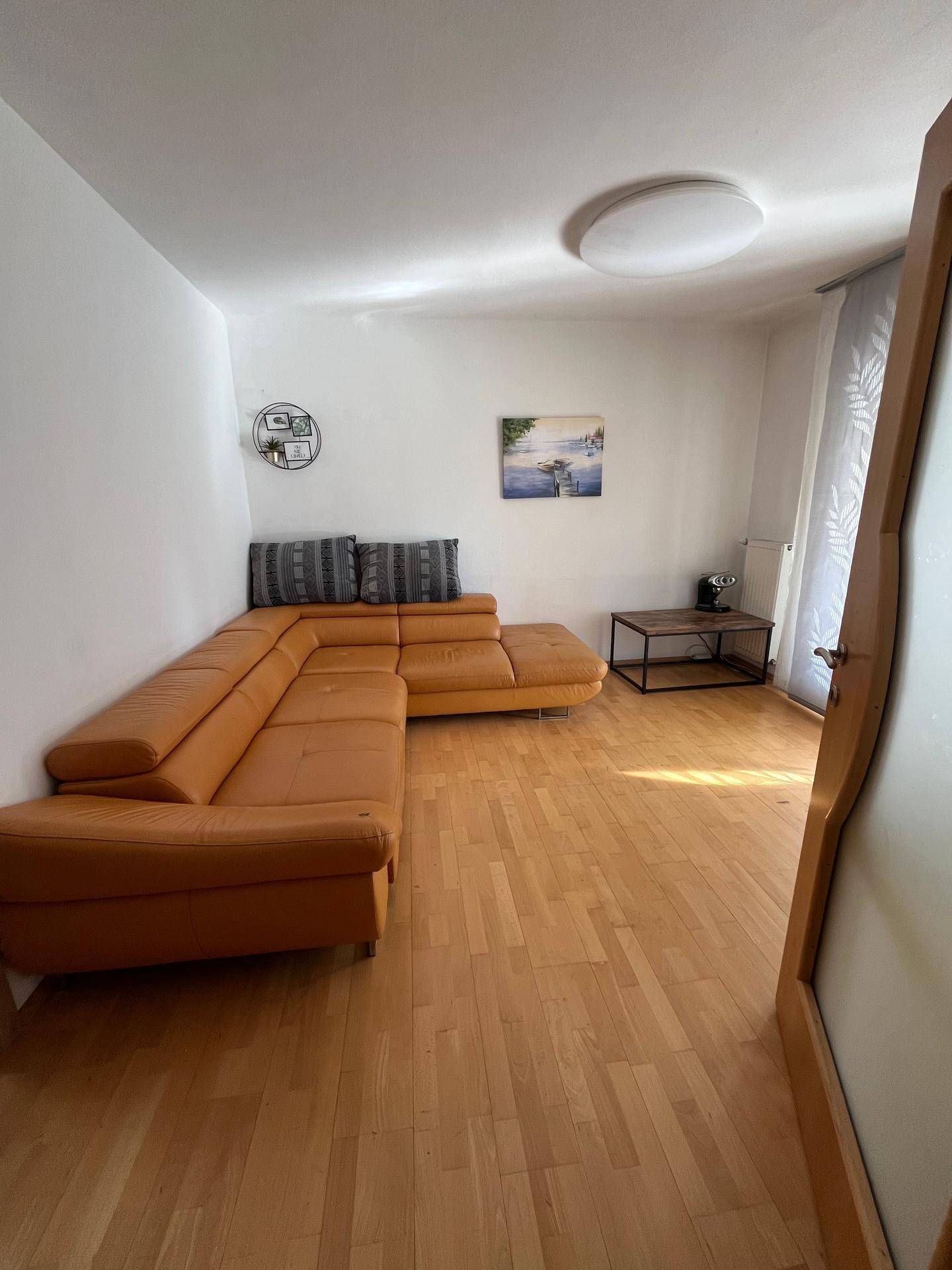 Gemütliches Wohnzimmer mit L-förmigem Ledersofa und hellem Parkettboden.