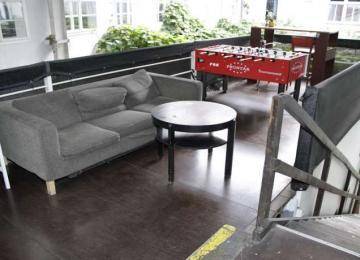 Gemütlicher Loungebereich mit Sofa, Couchtisch, Kickertisch und dunklem Holzboden.