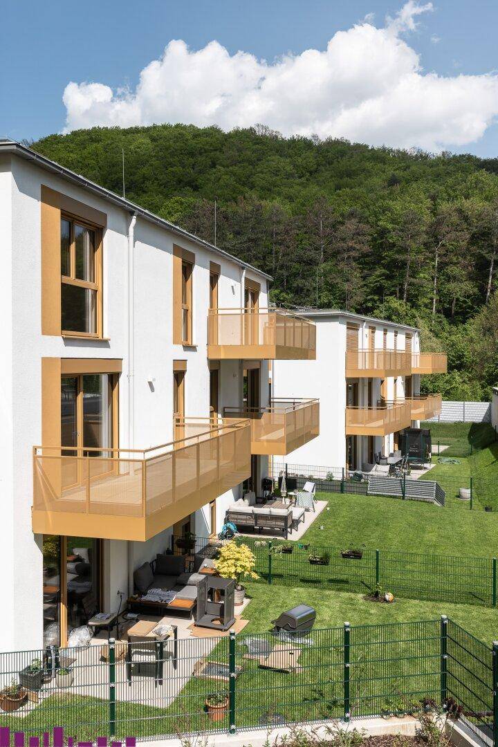 Nahaufnahme moderner Wohngebäude mit Balkonen, Terrassen und gepflegten Gärten.